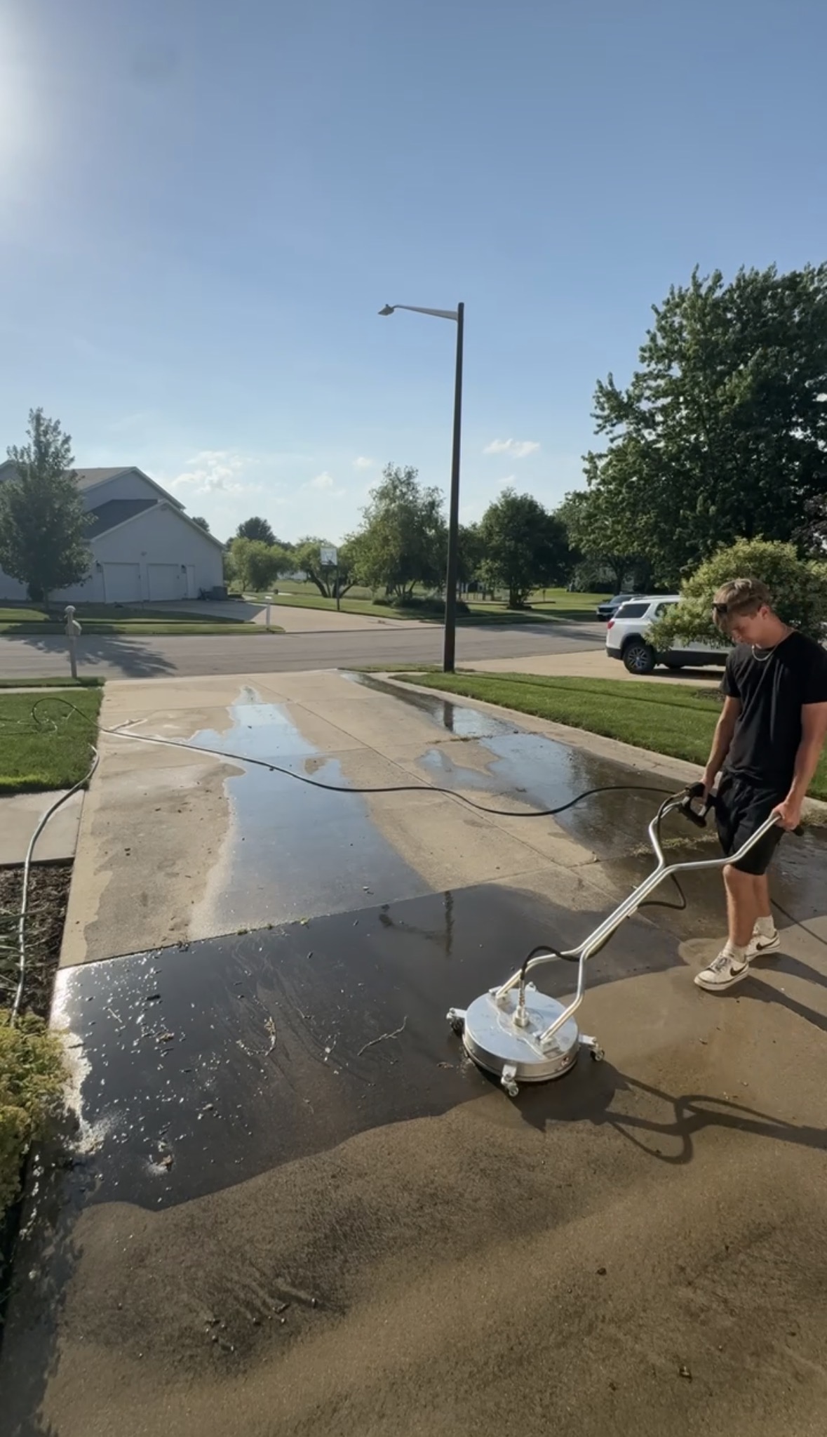 Prime Shine crew member using a rotary surface cleaner on a concrete driveway