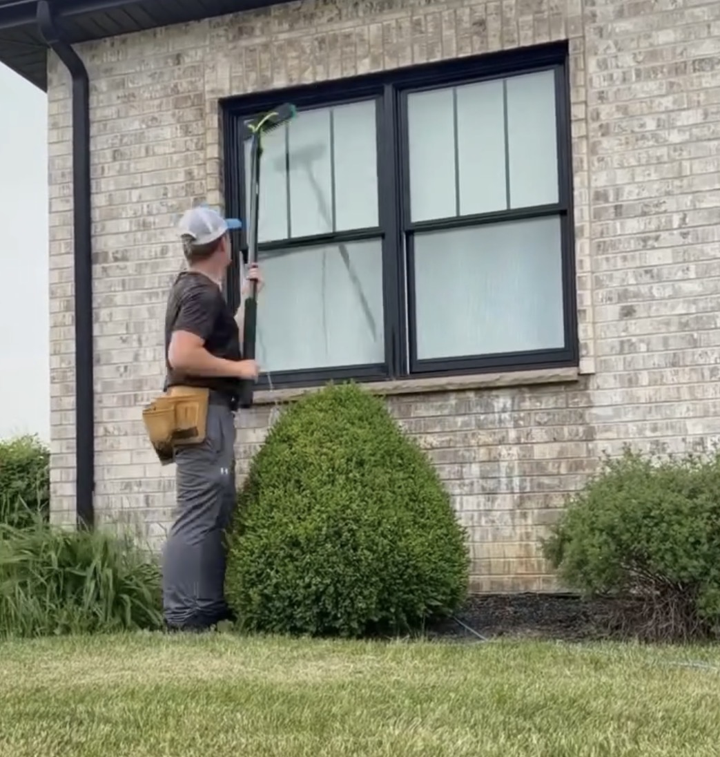 Prime Shine crew member washing exterior windows with a water-fed pole